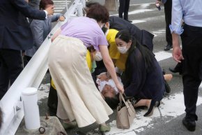 Бившият министър-председател на Япония Шиндзо Абе (в средата) пада на земята в Нара, Западна Япония, в петък