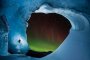  Една от новите му снимки показва катерач на дъгообразна ледена стена, на която полярното сияние блести в лилаво и зелено сред множество ярки звезди.
