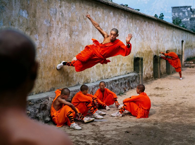 Млад монах от Шаолин тича хоризонтално през стена, интензивна концентрация